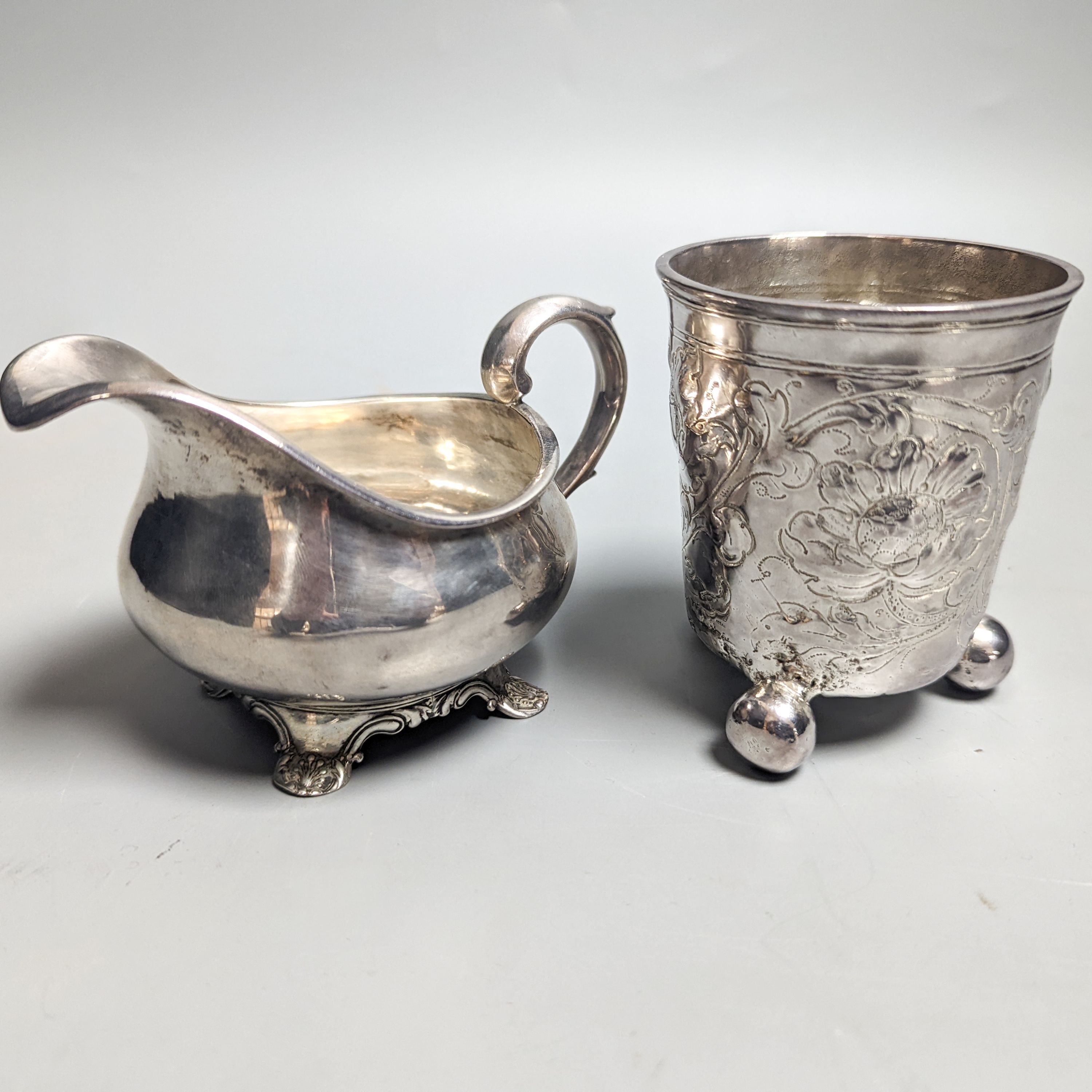 A William IV provincial silver cream jug, Barber & North, York?, 1836 and an 18th century continental embossed white metal beaker(a.f.), gross 6.5oz.